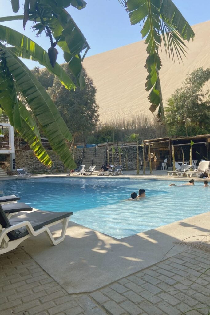 Solo Travel in Peru: A Guide From Someone Who Lives There 20 the pool from the hostel in Huacachina with the desert in the background