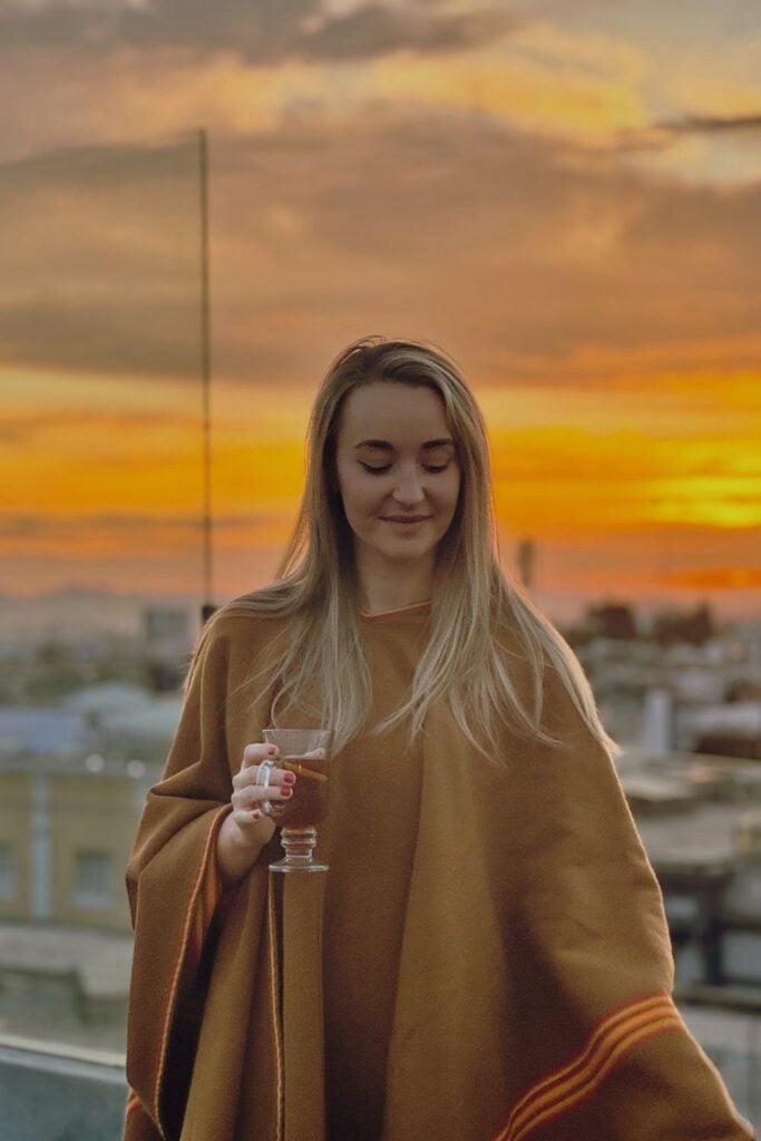 Peru Packing List: From Cusco to the Amazon 3 Girl looking down with a glass in hand with the sunset in the background in Peru