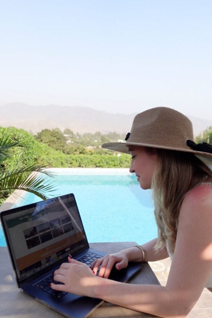 digital nomad on a laptop working on a laptop by the pool